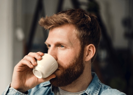 en mann drikker en kopp kaffe